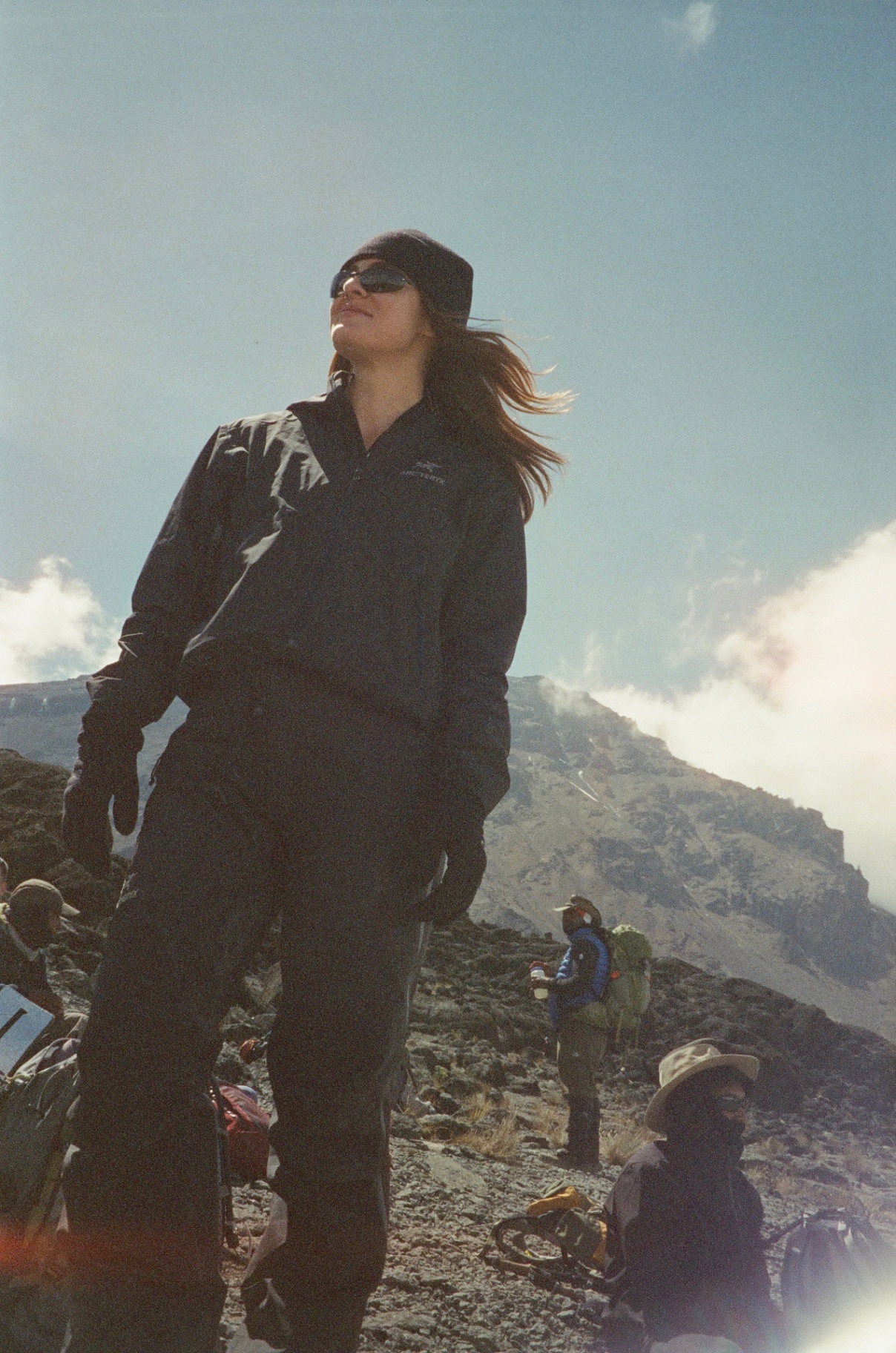 Portrait in a black shell jacket with wind in her hair on the ridge